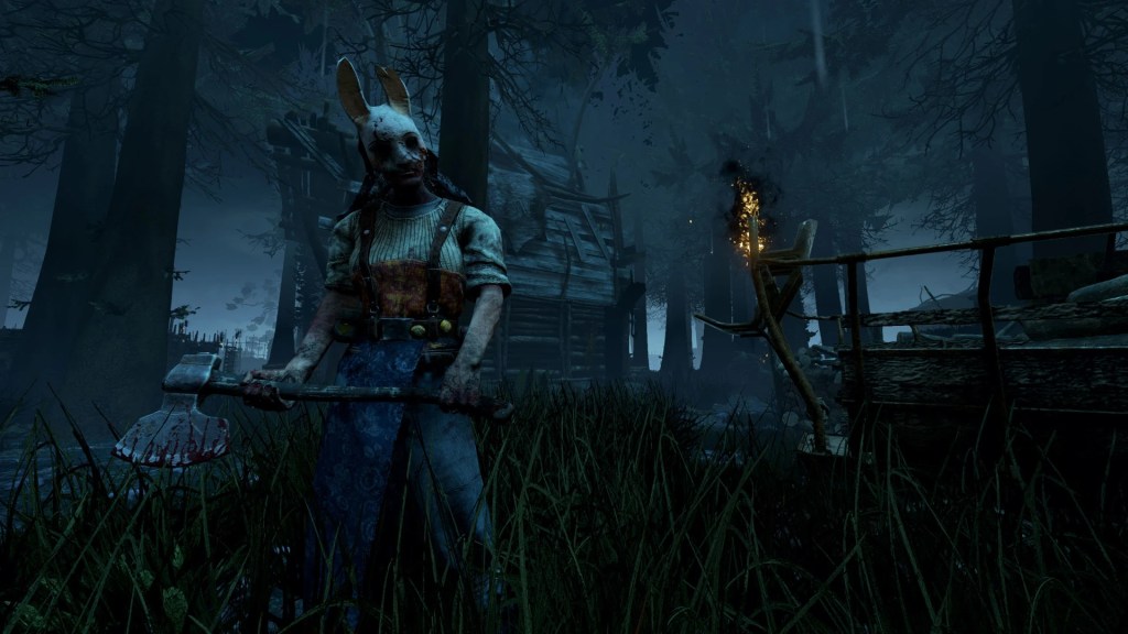 The Huntress from Dead by Daylight in a bloodstained rabbit mask and overalls wielding an axe in a dark, foggy forest near a wooden shack and a burning torch.