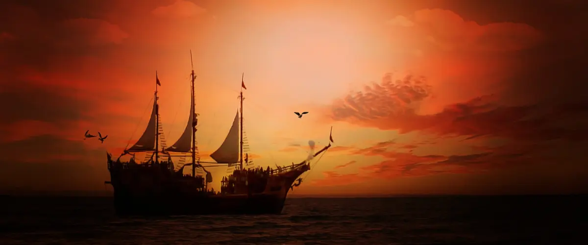 Silhouette of a sailing ship on the ocean with birds flying against a vibrant orange sunset sky.